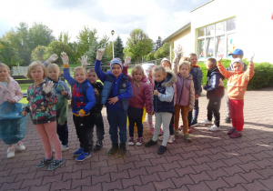 dzieci stoją przed przedszkolem w gumowych rękawiczkach i z workami na śmieci gotowi do zbieranie śmieci